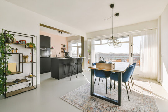 Wooden Dining Table Under Pendant Lamp In Open Plan Kitchen With Living Room