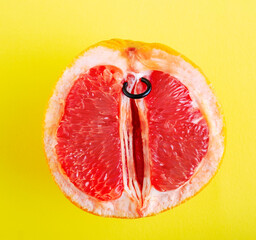Top view half of grapefruit with piercing ring on yellow background.