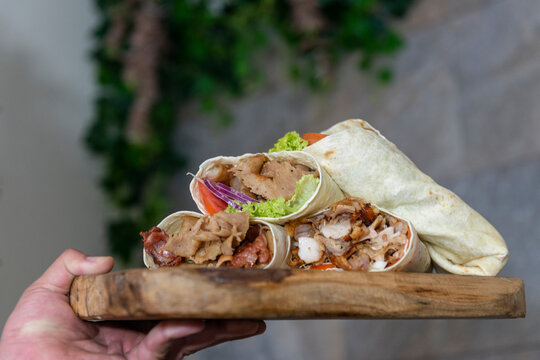 Mano que lleva una bandeja con diferentes tipos de Kebab en Durum 