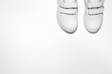 mock up flat lay two white women's sneakers with velcro fasteners with copy space isolated on a white background.
