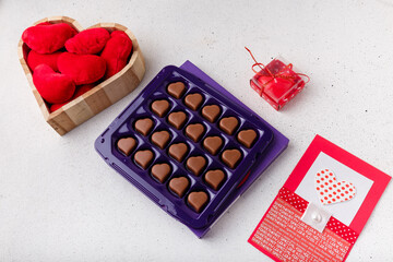 box of heart shaped chocolates, postcard, red candle, wooden box of fabric hearts on white. Valentines day 14 February present