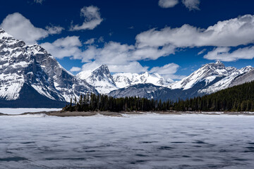 Upper Kananaskis Lake covered in melting frozen ice on a spring day in the Canadian Rocky Mountains near Banff.
