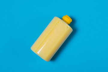 Yellow dishwashing detergent with banana scent on a blue background with copy space