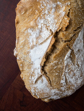 Close Up, top view of a loaf of bread on a dark wooden board