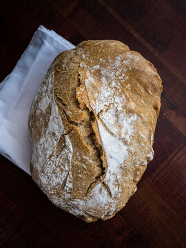 Top view of a loaf of bread on a wooden board and white napkin