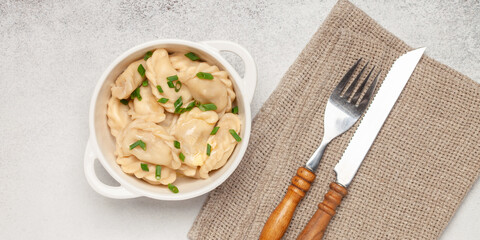 Appetizing homemade Russian dumplings pelmeni stuffed with meat mince with butter in a bowl on the table. Top view