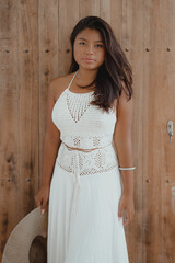 Fototapeta premium young serious Indonesian woman in white maxi dress with hat in hand