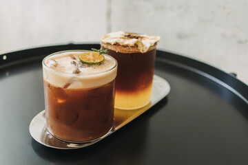 Two iced yusu orange coffee special drinks served on black table in the cafe.