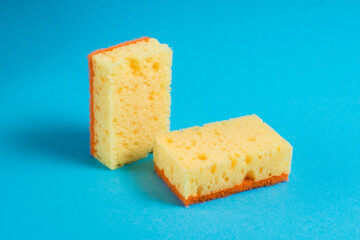 Yellow porous sponges for cleaning on a blue background with copy space. Home cleaning concept