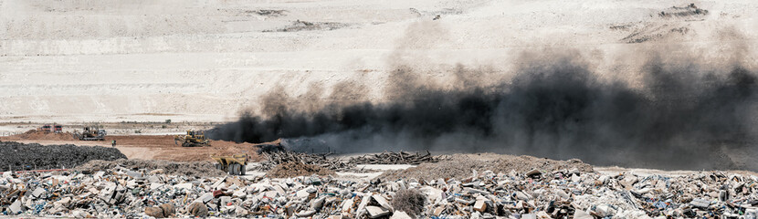 Fire at landfill site. Panorama of black smoke over burning old tyres and piles of garbage