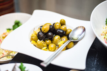 Plate with olives. Served on a plate with lemon. A buffet line with appetizers.