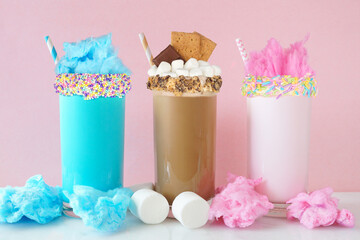 Fun colorful summer milkshakes against a pastel pink background. Blue and pink cotton candy and...