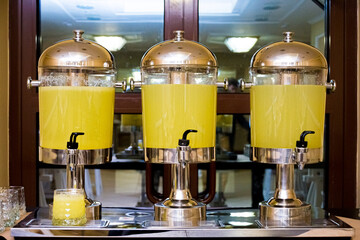 Three beverage dispensers with lemonade standing on the table. Refreshment drinks. Self serving...