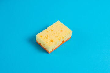 Yellow porous sponge for cleaning on a blue background with copy space. Home cleaning concept