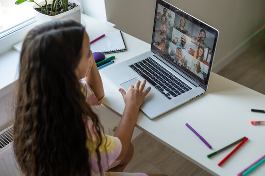 Home schooling. A girl is sitting at a table with a laptop during an online video chat of a school lesson with a teacher and class. Concept of distance education. Self-isolation in quarantine.