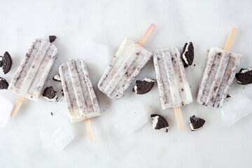Cookies and cream ice pops scattered over a white marble background
