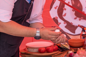 The cook holds two halves of an egg in his hands