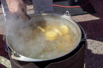The cook is stirring the cauldron with a spatula where the ear is being prepared