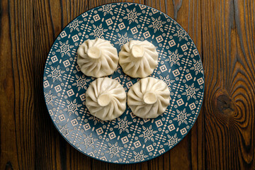 Georgian cuisine. Hinkali in plates on a wooden table
