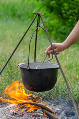 a pot in which soup is cooked on a tripod stands on a fire