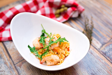A portion of risotto with shrimp, seafood and arugula in a deep boat plate