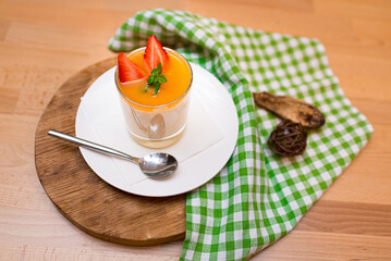 dessert in a glass parfait with strawberries and mango sauce. one portion. view slightly above.