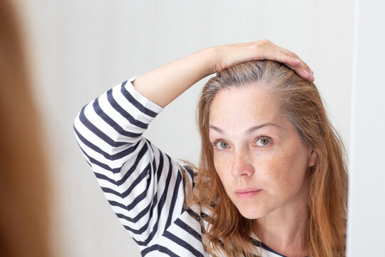 Middle Aged Woman Looking At Gray Hair In Mirror Reflection On Growing Out Root