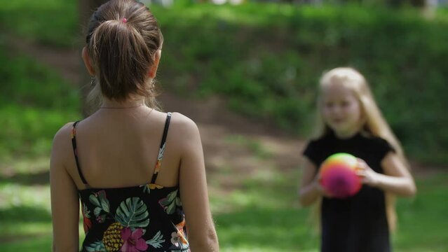 Two little girls playing with ball in the green park