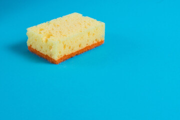 Yellow porous sponge for cleaning on a blue background with copy space. Home cleaning concept