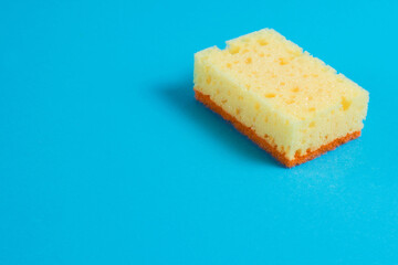 Yellow porous sponge for cleaning on a blue background with copy space. Home cleaning concept