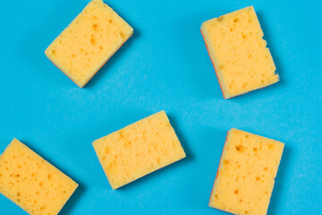 Yellow sponges for washing dishes and cleaning on a blue background flatlay