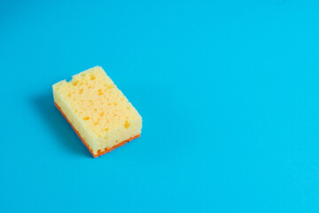 Yellow porous sponge for cleaning on a blue background with copy space. Home cleaning concept