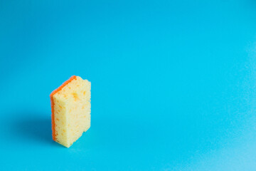 Yellow porous sponge for cleaning on a blue background with copy space. Home cleaning concept