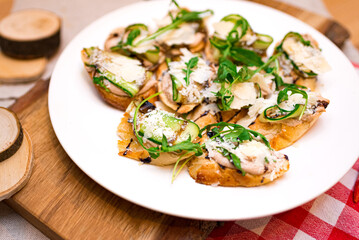 A plate of bruschetta with spreads, cheese, arugula. Many servings of delicious appetizers.
