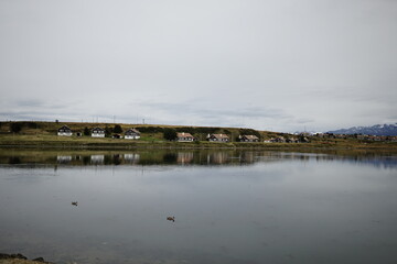 the photo captures the beautiful landscape of the city of Ushuaia, with houses of Argentine architecture and a beautiful view of the lake.