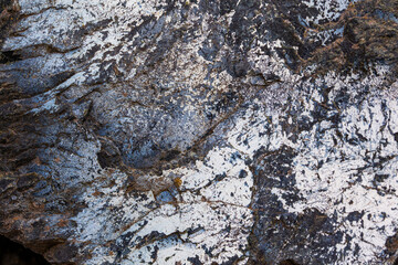 Texture of an old stone with cracks and scratches close-up.