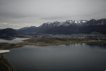 the photo captures the moment of takeoff and flight by plane over Ushuaia — a city and port in...