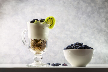 Muesli, yogurt, honeysuckle and kiwi in a transparent glass. Delicious and healthy breakfast