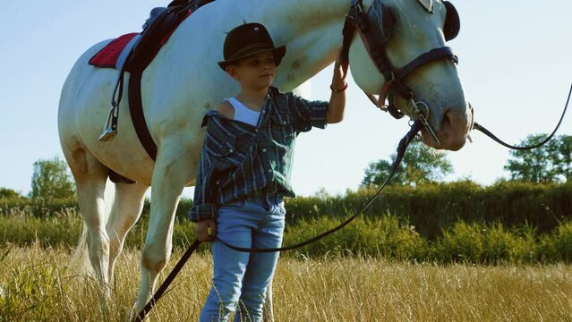 Little boy is playing with his pet on a farm holding a horse by a leash