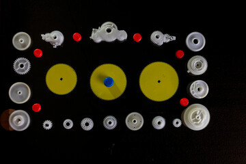 plastic gears made of white fluoroplast , spare parts for office equipment on a black background, upper angle.
