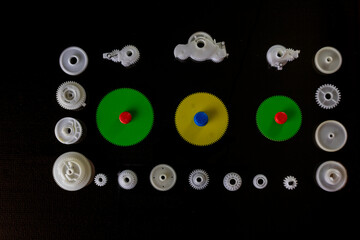 plastic gears made of white fluoroplast , spare parts for office equipment on a black background, upper angle.