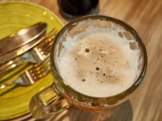 Mug of frothy beer on the table before dinner.