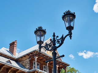 Decorative street lamp near a wooden house.