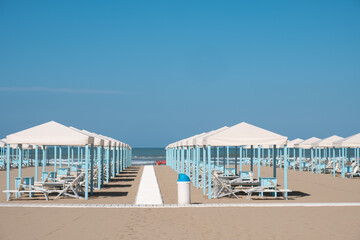 Obraz premium Blue and white beach cabanas lined up and ready for the day's beachgoers in Viareggio, Italy.
