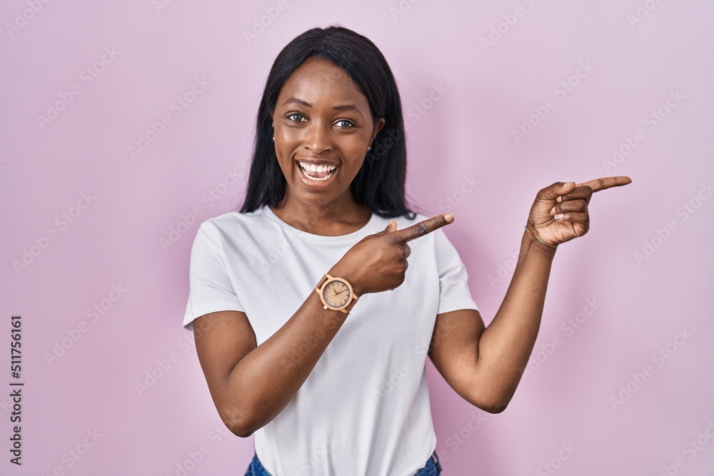 Sticker African young woman wearing casual white t shirt smiling and looking at the camera pointing with two hands and fingers to the side.