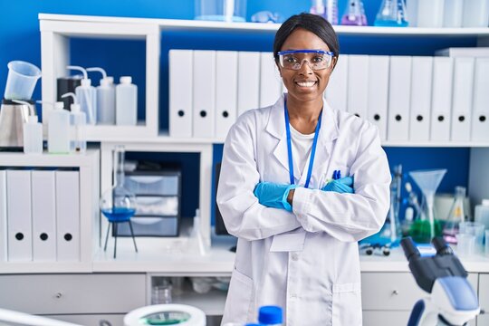 Young african american woman scientist smiling confident standing with arms crossed gesture at laboratory
