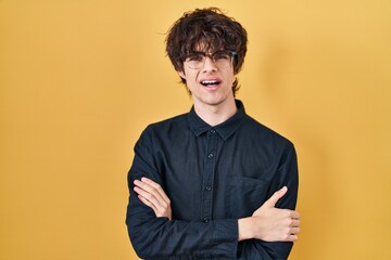 Obraz premium Young man wearing glasses over yellow background skeptic and nervous, disapproving expression on face with crossed arms. negative person.