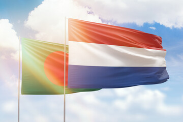 Sunny blue sky and flags of netherlands and bangladesh