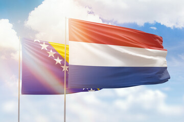 Sunny blue sky and flags of netherlands and bosnia