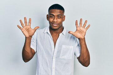 Young black man wearing casual white shirt showing and pointing up with fingers number ten while smiling confident and happy.
